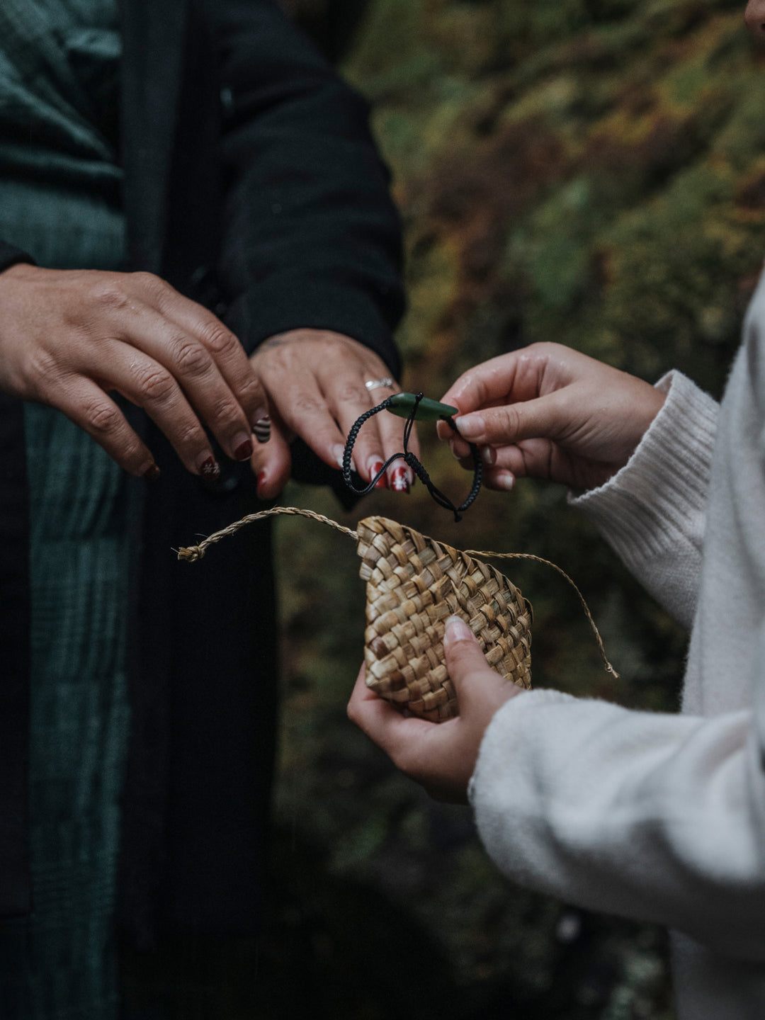 A pounamu greenstone bracelet being handed from one person to another